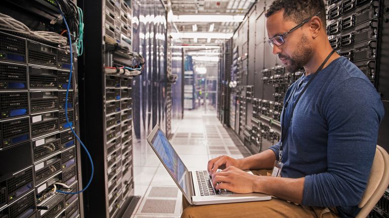 A man using laptop in server room