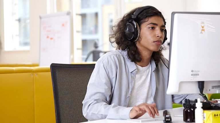 A man wearing headphones uses a computer in an office space